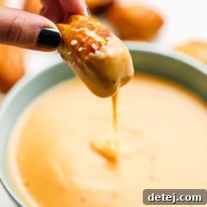 square photo of a pretzel being dipped into vegan beer cheese sauce