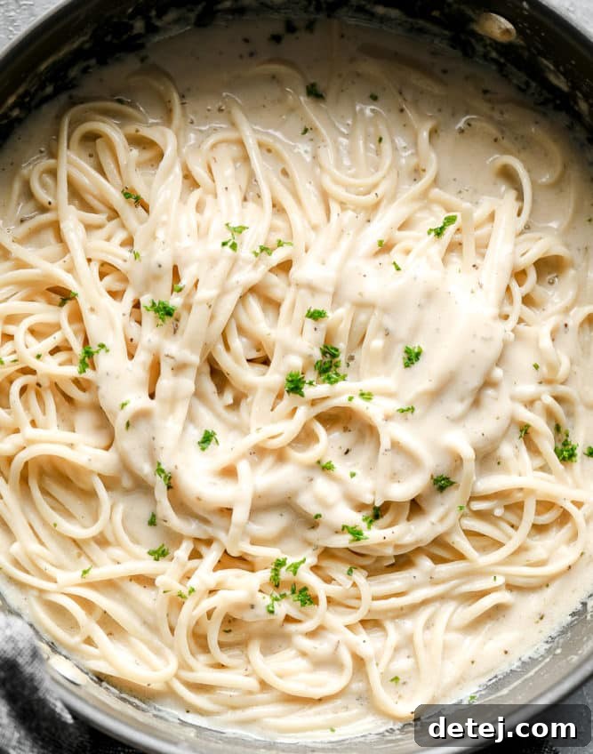 pan full of creamy pasta and white sauce, sprinkled with green parsley