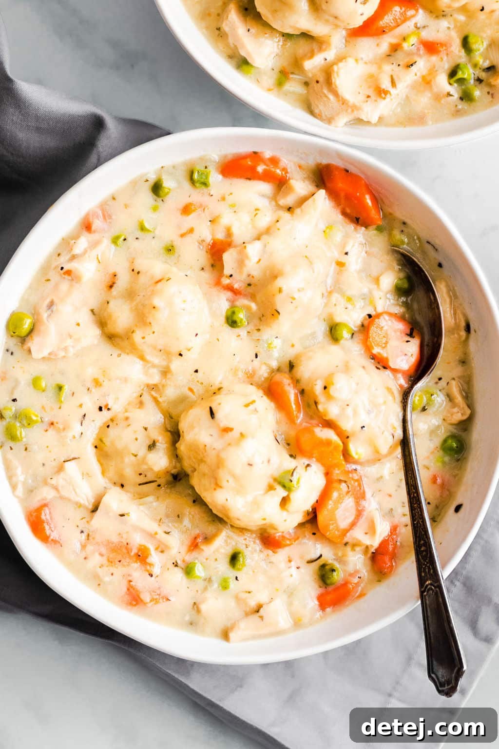 A pristine white bowl brimming with hearty vegan chicken and dumplings, showcasing the creamy broth and plump dumplings.