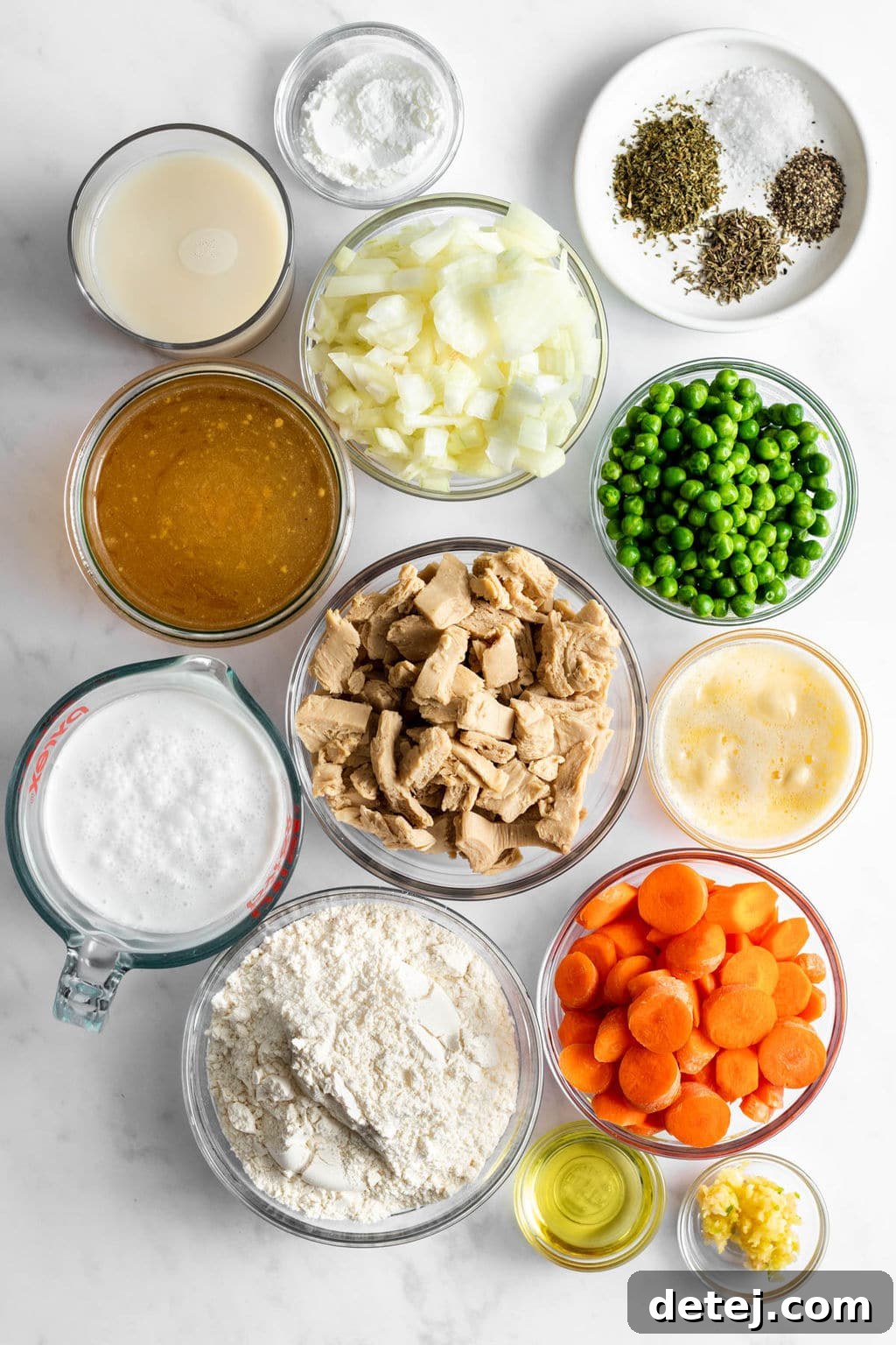 Individual glass bowls displaying prepared ingredients: vegan chicken pieces, diced vegetables, dried herbs, flour, vegetable broth, and baking powder, ready for cooking.