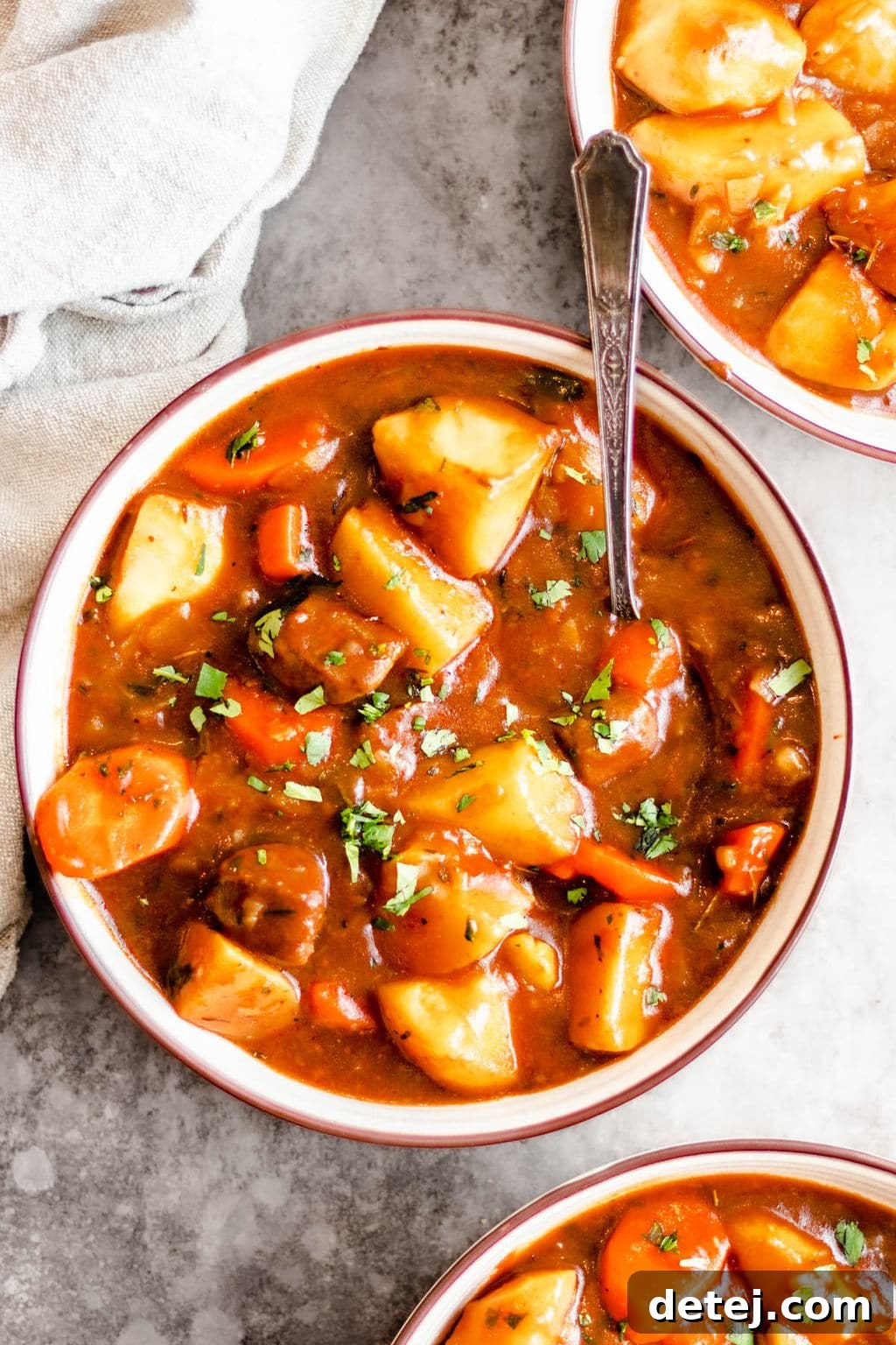 Two bowls filled with hearty vegan Irish stew, garnished with fresh herbs, ready to be served.