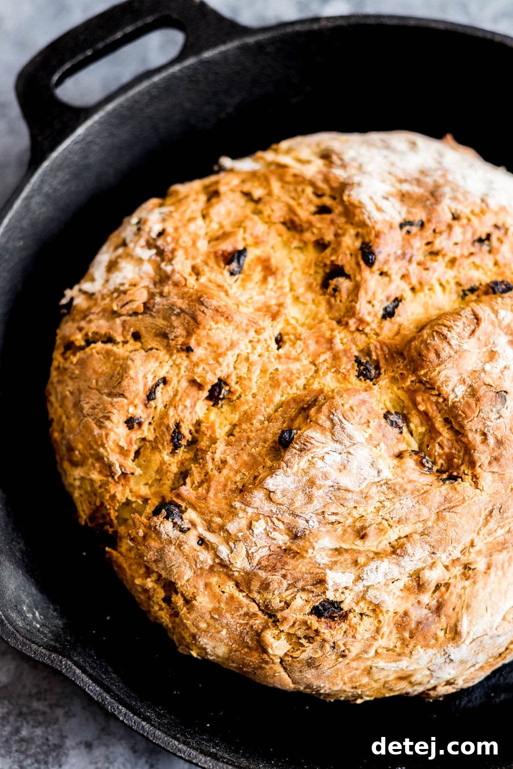 Freshly baked vegan Irish soda bread in a black cast iron pan, ready to be sliced.