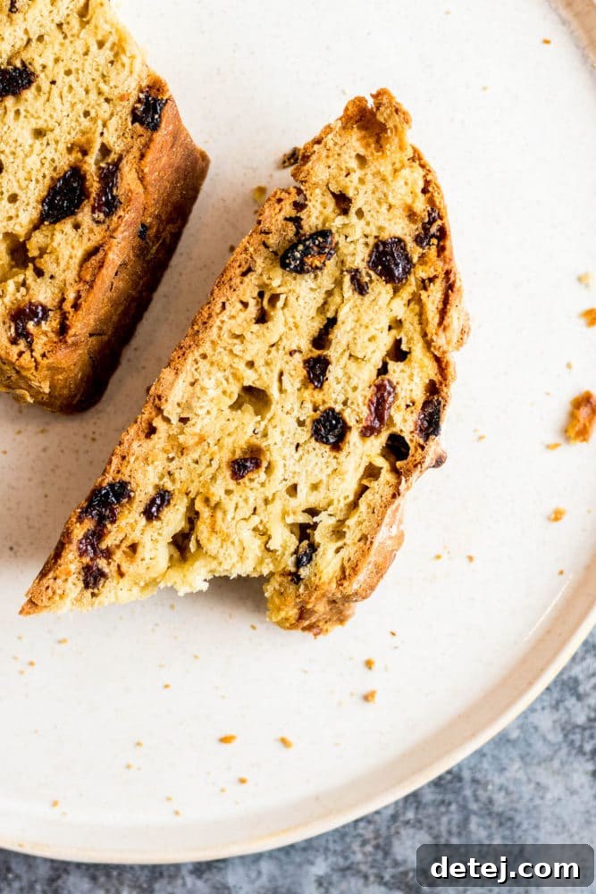 A perfectly sliced piece of vegan Irish soda bread on a white plate, revealing its soft interior.