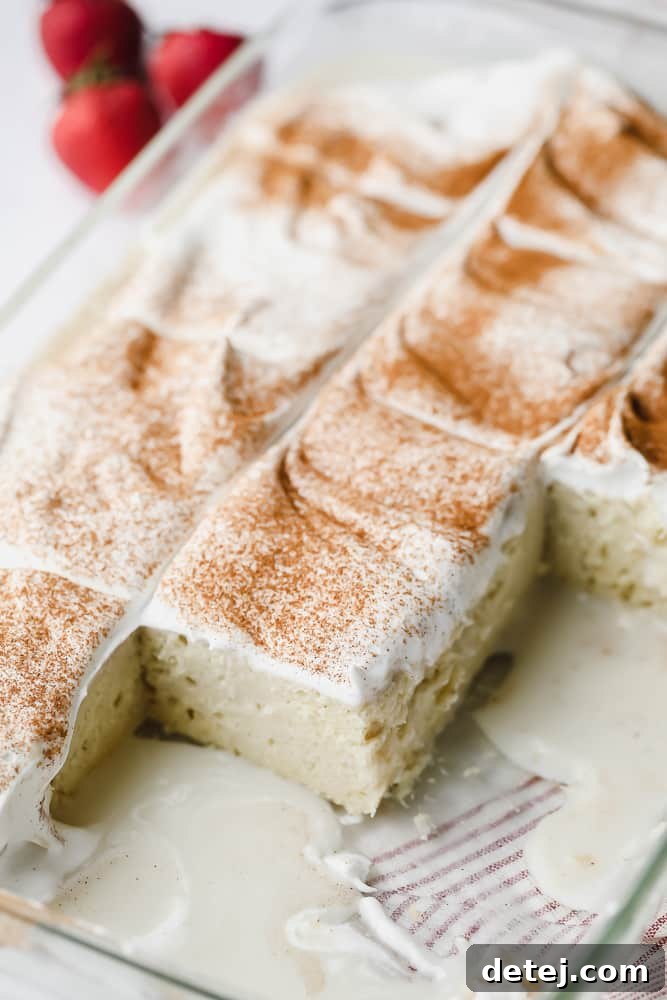 A clear glass baking pan showcasing the bottom of the milk-soaked cake, with visible milk mixture pooled at the base, indicating thorough saturation.
