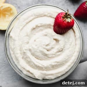 looking down on a bowl filled with creamy white mixture and strawberries, grey background