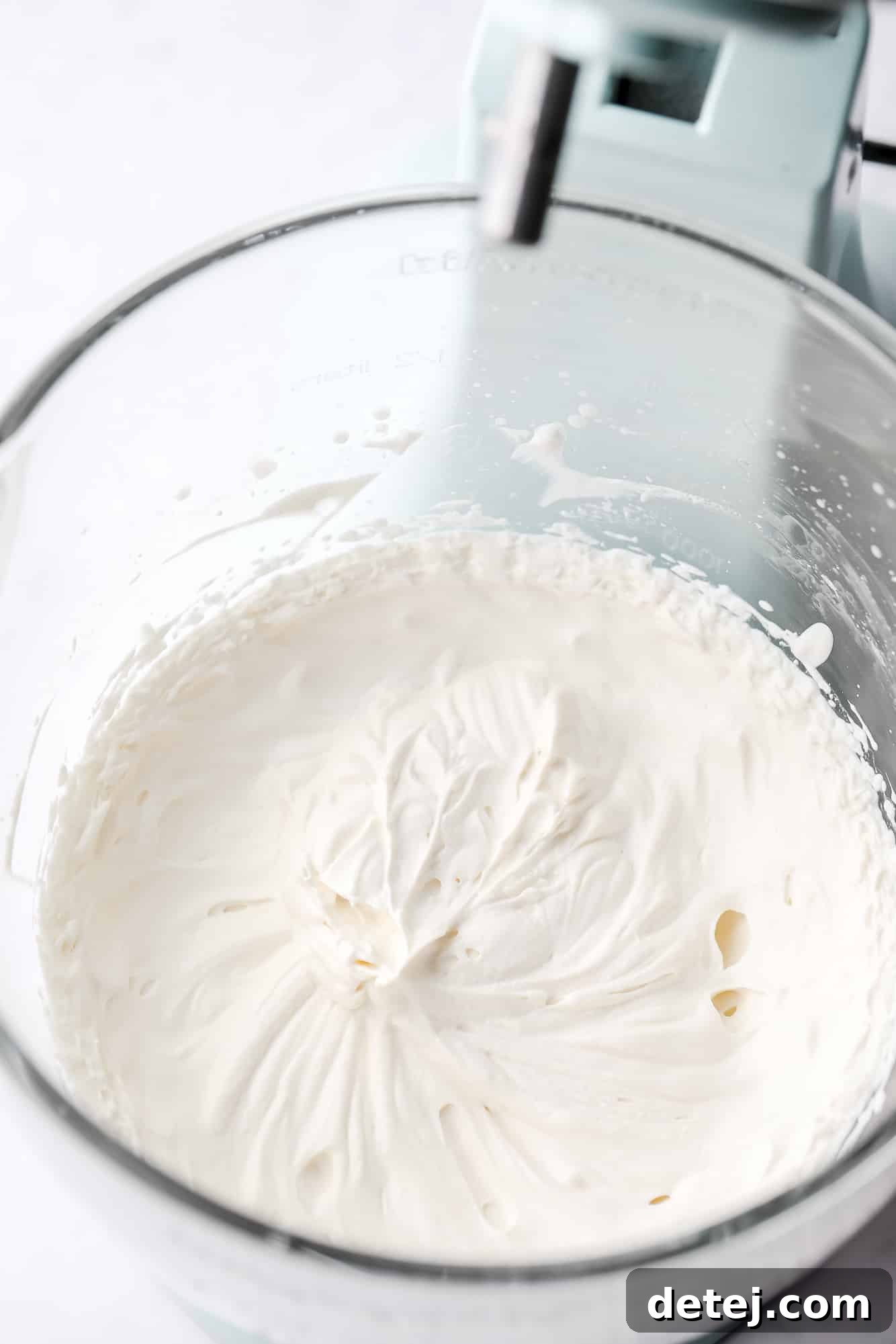 vegan whipped cream in the glass bowl of a standing mixer.