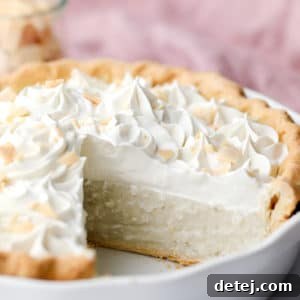 A slice of vegan coconut cream pie on a white plate, showcasing the creamy filling and whipped topping.