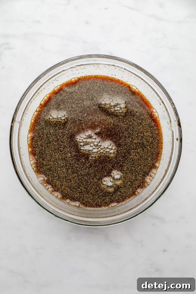 A close-up of a rich, brown sauce with small bubbles, resting in a clear glass bowl, indicating its readiness to be used in the recipe.