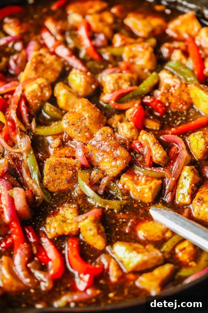 A full pan of Black Pepper Tofu with vibrant peppers and onions, generously coated in a rich, glossy sauce, ready for serving.