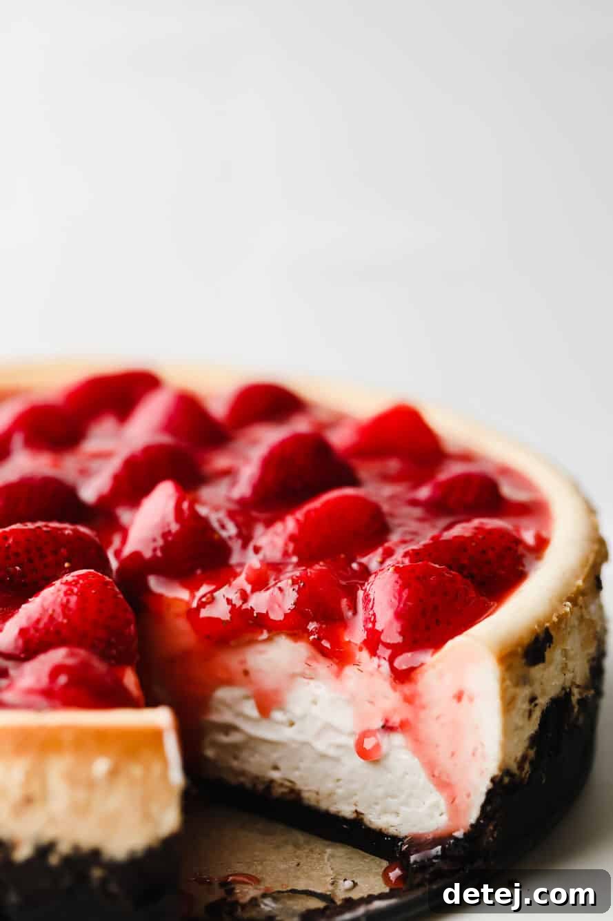 A beautifully sliced vegan strawberry cheesecake, revealing its creamy layers and rich Oreo crust.