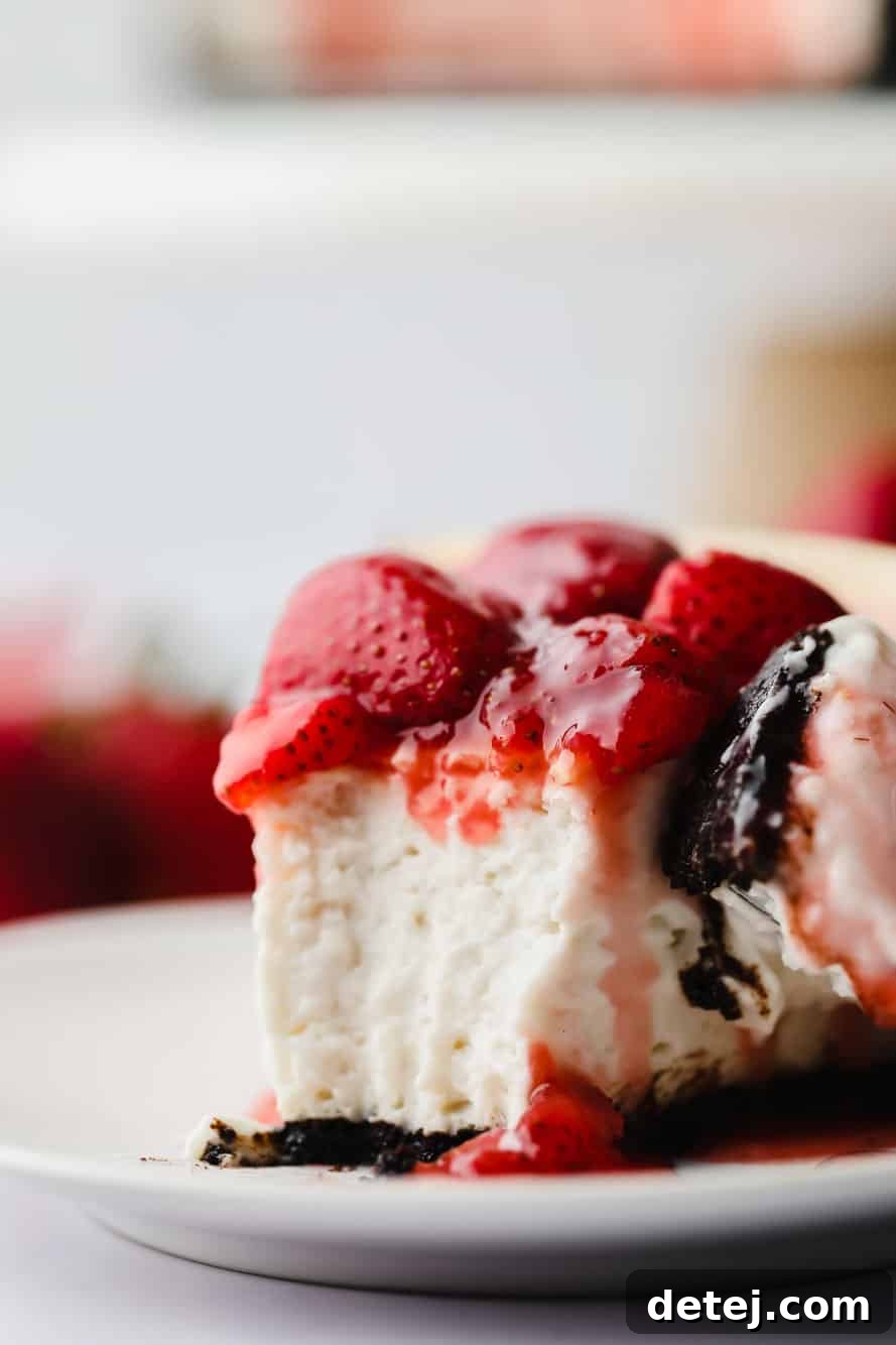 A close-up of a slice of vegan strawberry cheesecake with a bite taken, highlighting the rich filling and sauce.