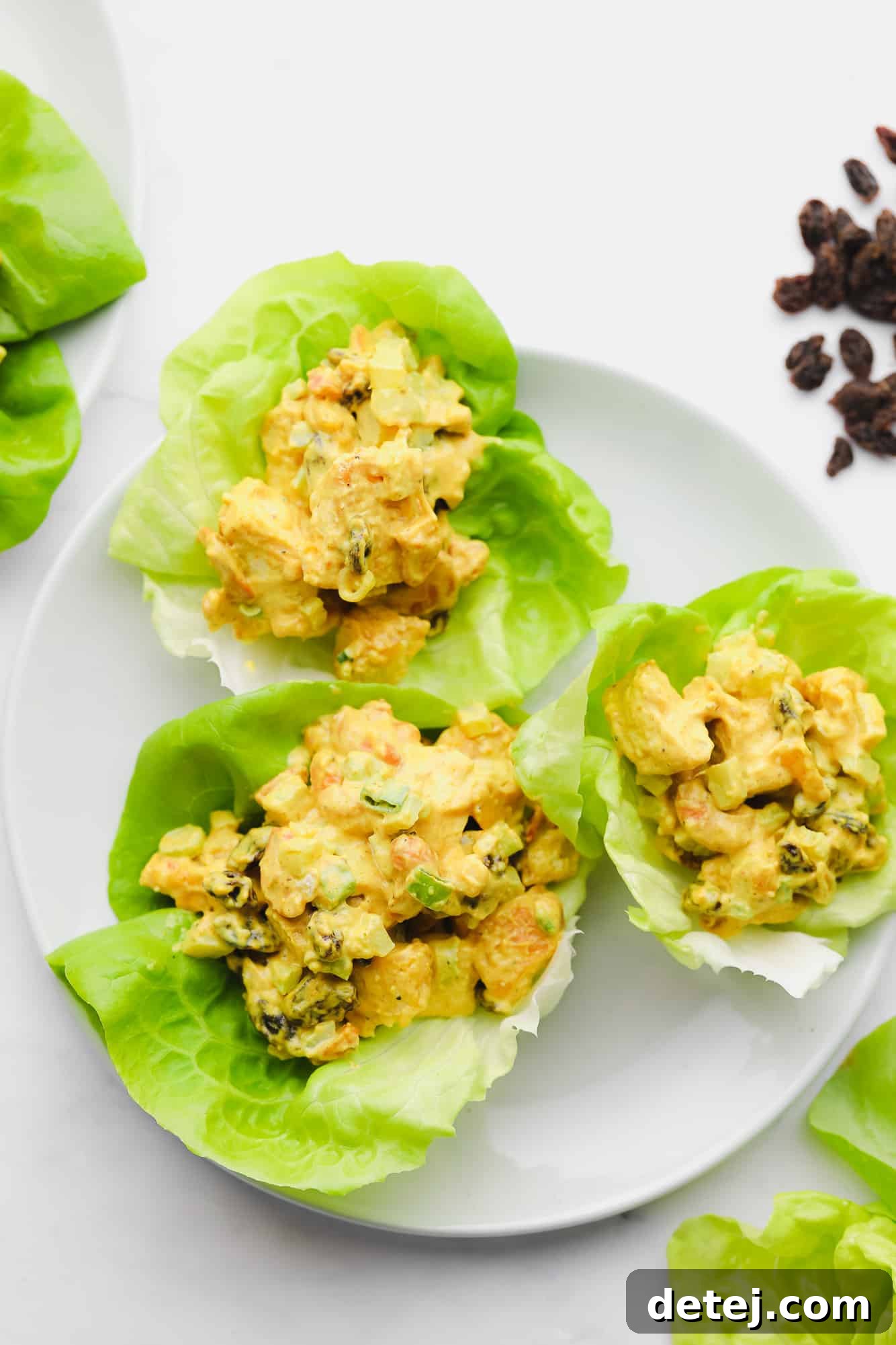 Golden Curried Tofu Salad 3 3 lettuce cups filled with tofu salad on a white plate.