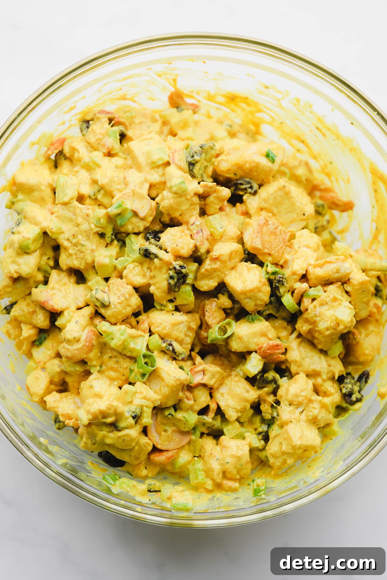 Golden Curried Tofu Salad 7 vegetables, baked tofu, and a creamy yellow sauce stirred together in a large glass bowl.