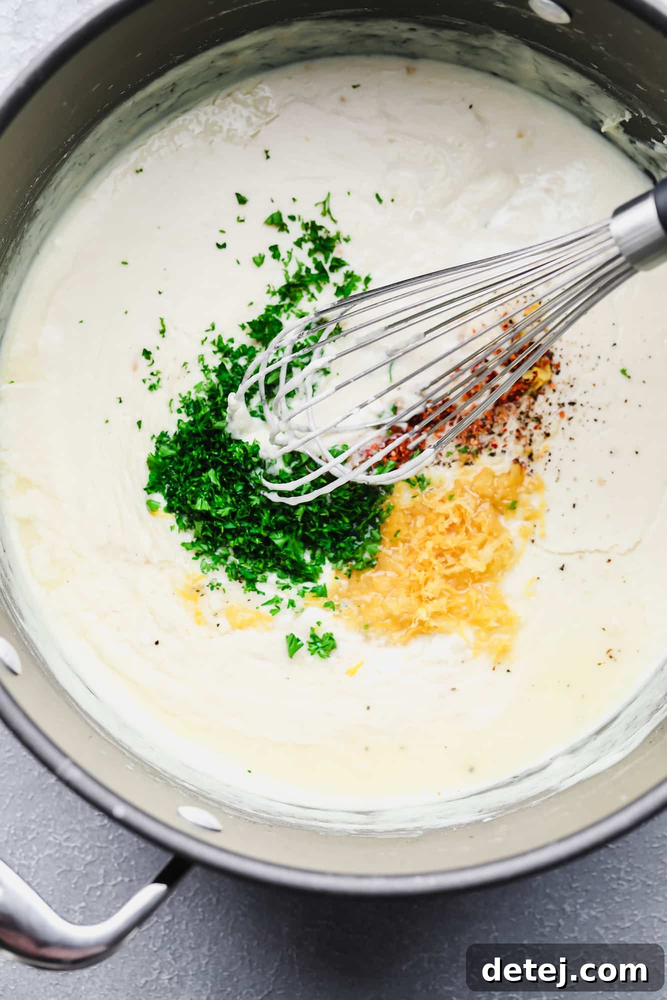 Whisking fresh lemon zest, vibrant parsley, and a hint of red pepper flakes into a white cream sauce in a pot.