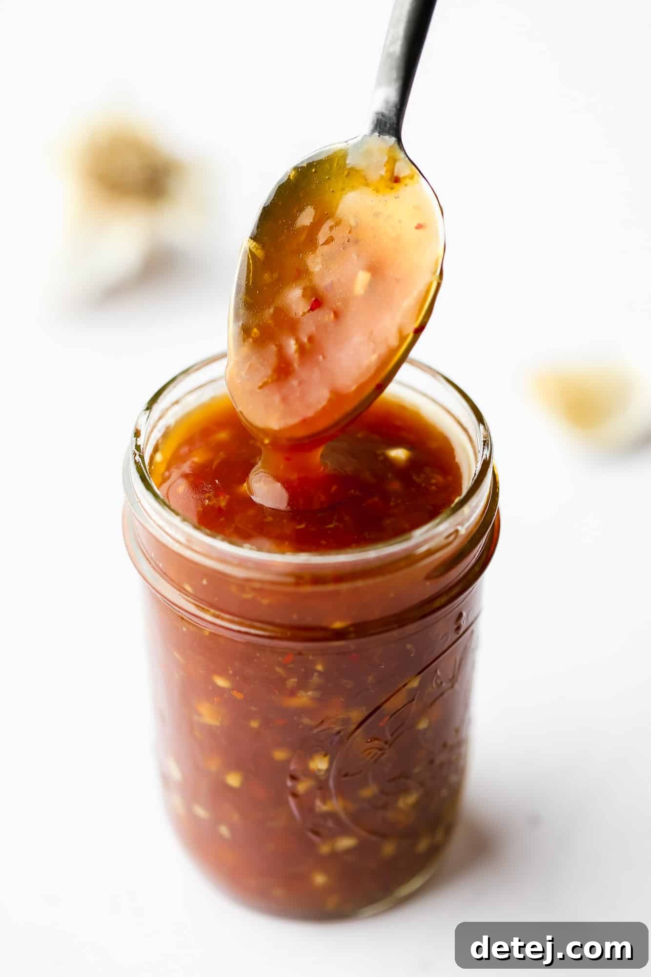 Effortless 5 Minute Stir Fry Sauce 2 A sauce-covered spoon emerging from a glass jar filled with homemade stir fry sauce, ready for use.