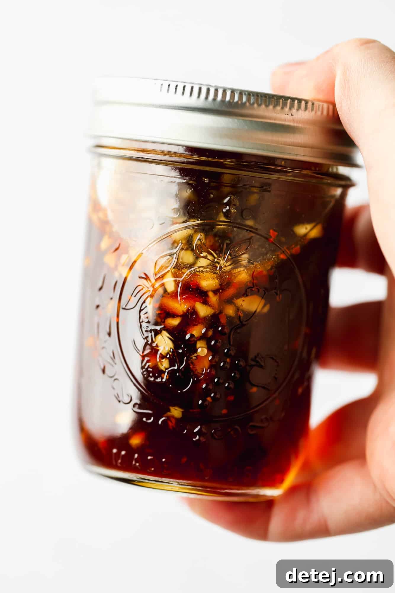 Effortless 5 Minute Stir Fry Sauce 4 A woman's hand holding a mason jar filled with freshly made stir fry sauce, ready for storage or immediate use.