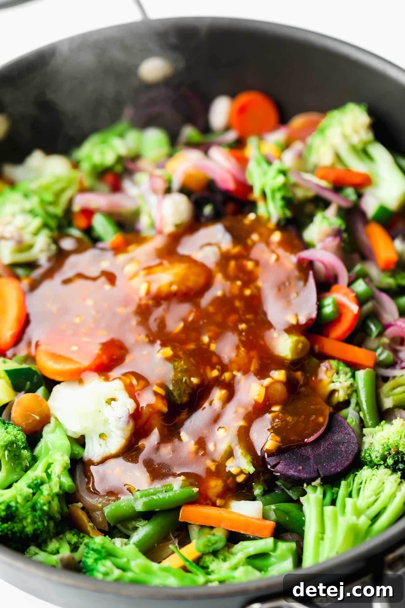 Effortless 5 Minute Stir Fry Sauce 5 Stir fry sauce being poured over a colorful medley of vegetables and protein cooking in a black skillet, creating a delicious meal.