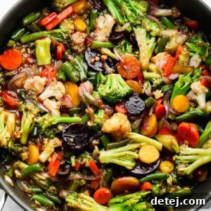 Close up of sauce-covered cooked vegetables in a large black skillet.