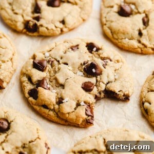 A vegan gluten-free cookie with a bite taken out, showing its soft interior, and a sprinkle of salt on top.