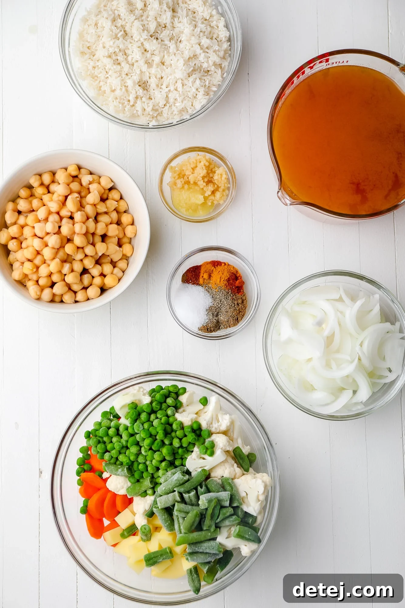 Individual glass bowls displaying all the prepped ingredients for Easy Vegan Biryani, including spices, vegetables, and rice.
