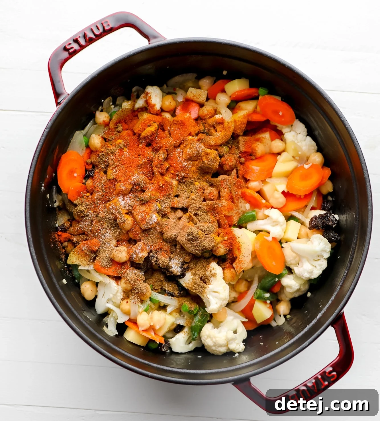A large black pot filled with a colorful mix of vegetables and Indian spices, ready to be cooked into biryani.