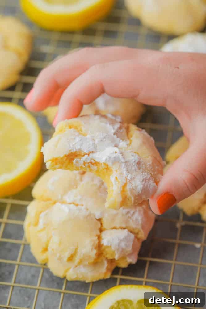 hand picking up a yellow cookie from stack of others on cooling rack