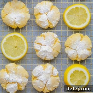 square image of several yellow cookies with powdered sugar and lemon slices on cooling rack