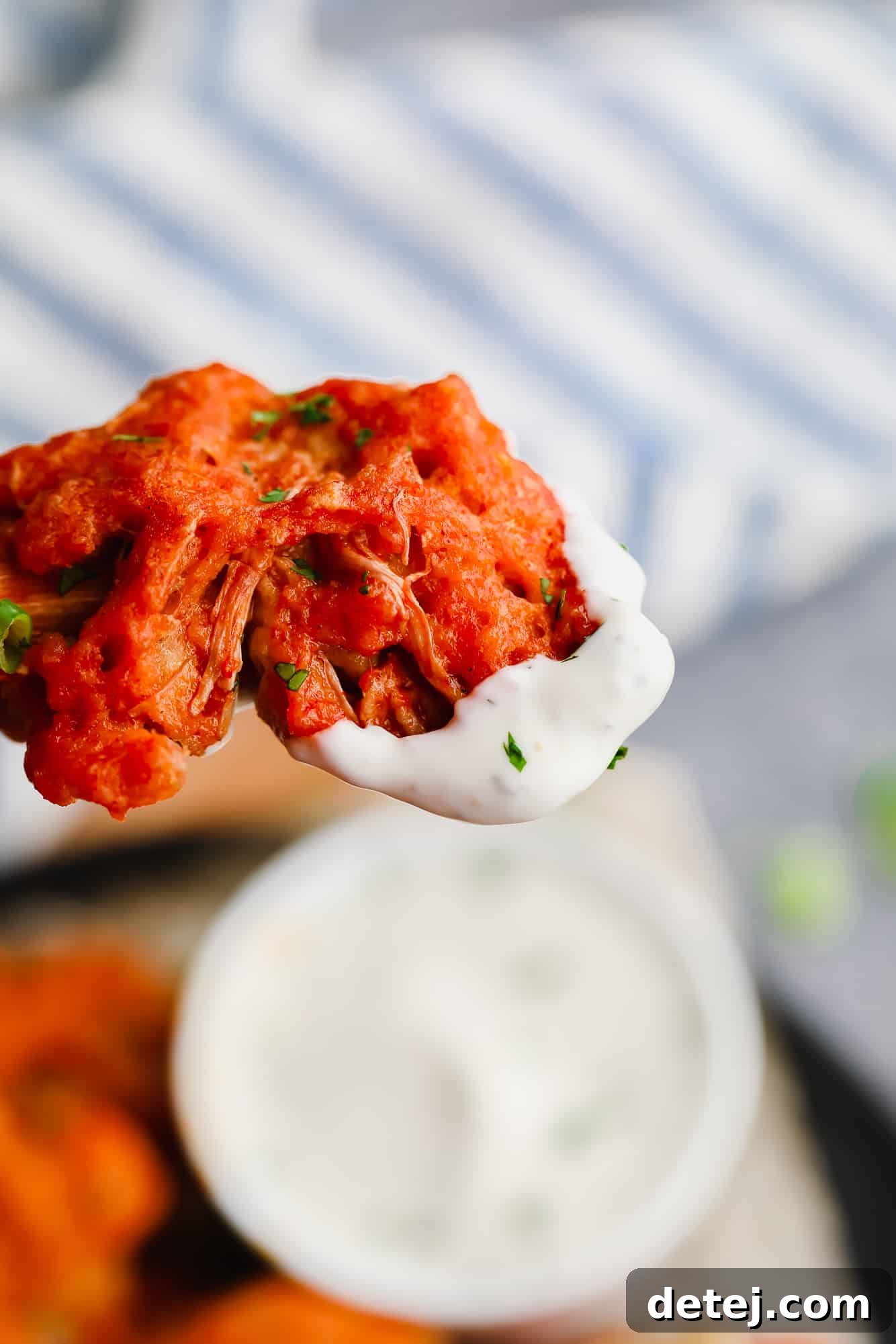 Wingless Wonders 3 A close-up shot of a single vegan wing, perfectly sauced and dipped into a rich, white dipping sauce, highlighting its tender, meaty interior.