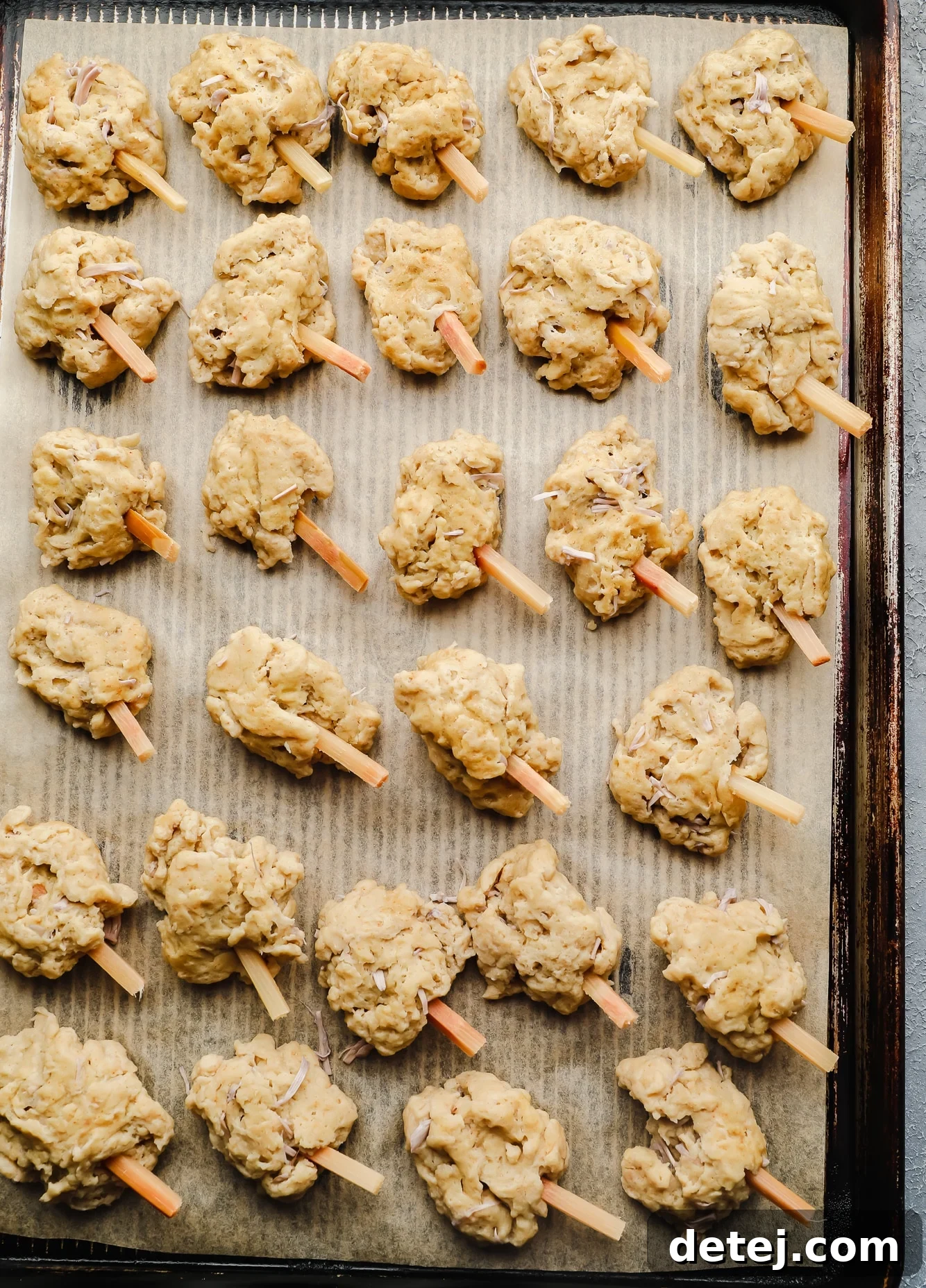 Wingless Wonders 8 Unbaked vegan wings, neatly arranged on a parchment-lined baking sheet, some with sugar cane sticks inserted, ready to go into the oven.