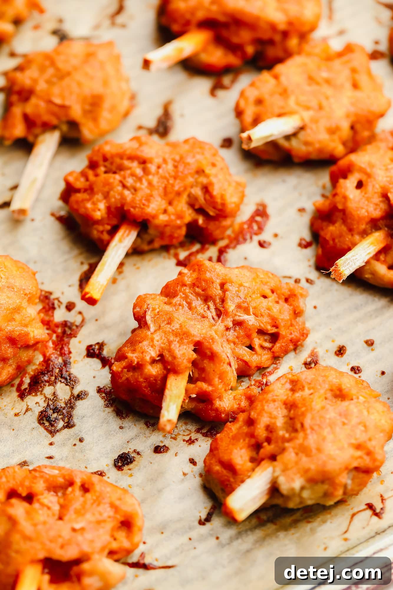 Wingless Wonders 10 A close-up view of baked, perfectly textured orange "meat" pieces, fresh out of the oven, on a parchment-lined baking sheet, ready for saucing.