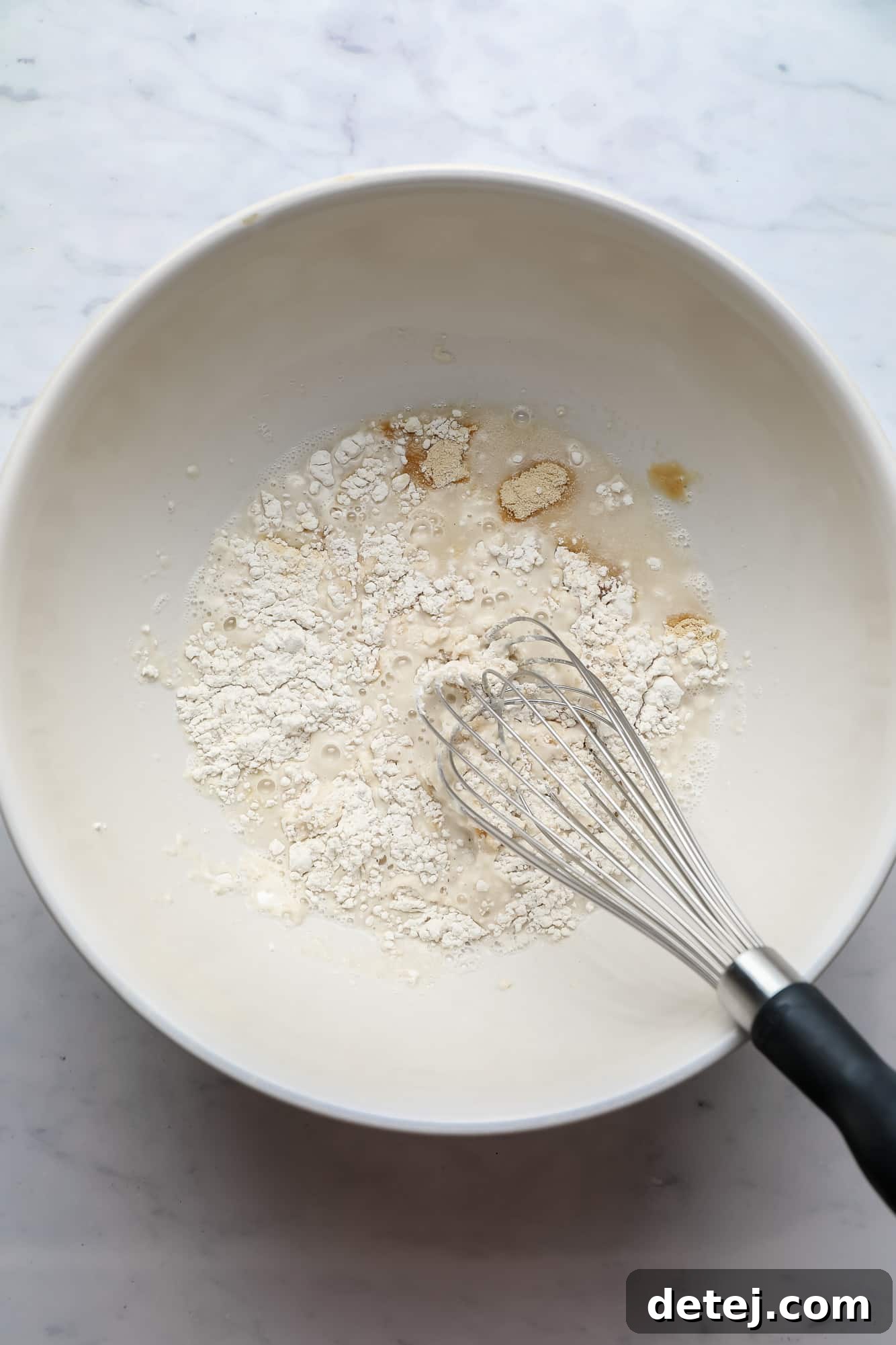 breading ingredients for cauliflower wings being whisked together in a large white bowl.
