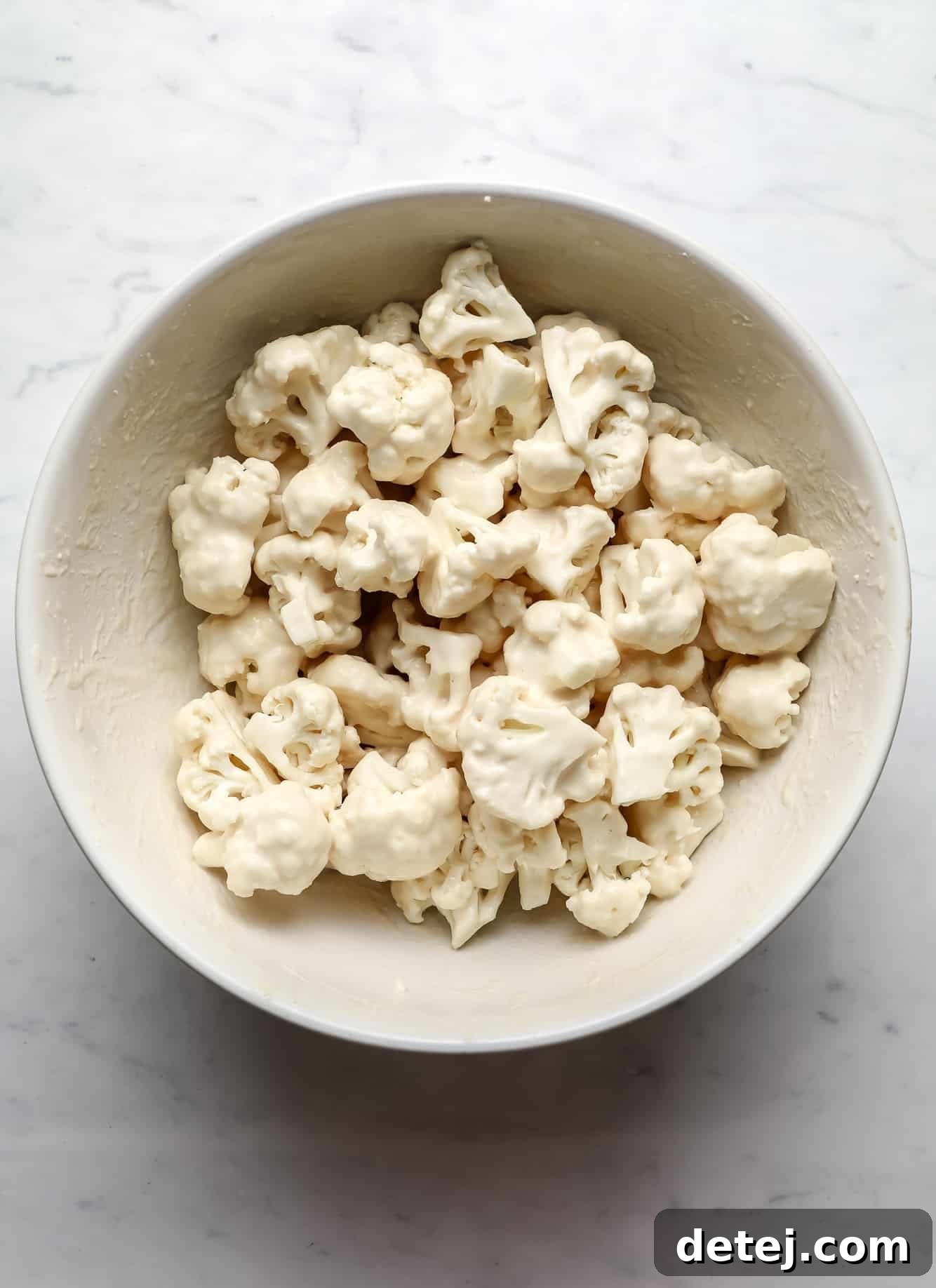 breaded cauliflower florets in a large white bowl.