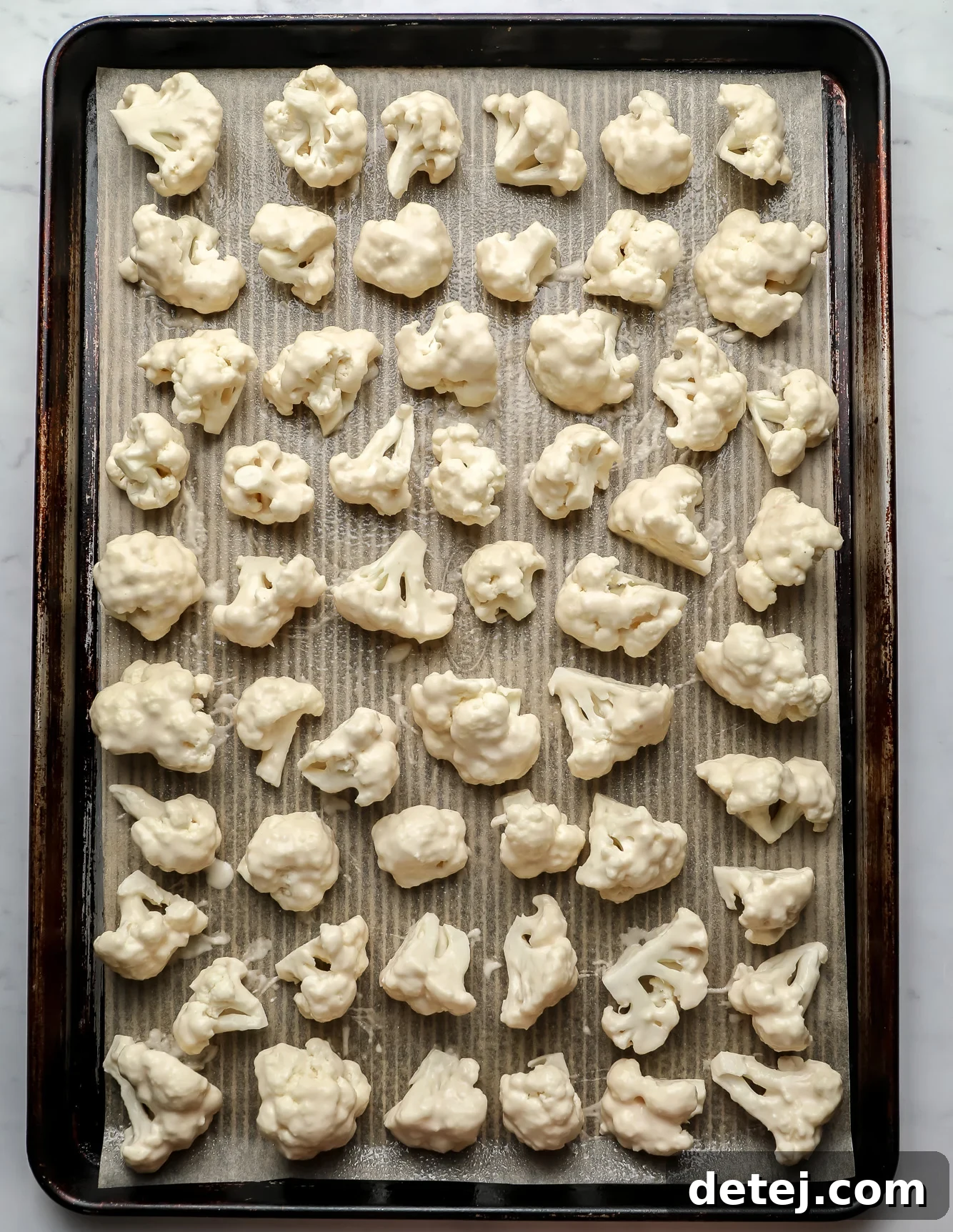 breaded cauliflower in rows on a baking sheet.