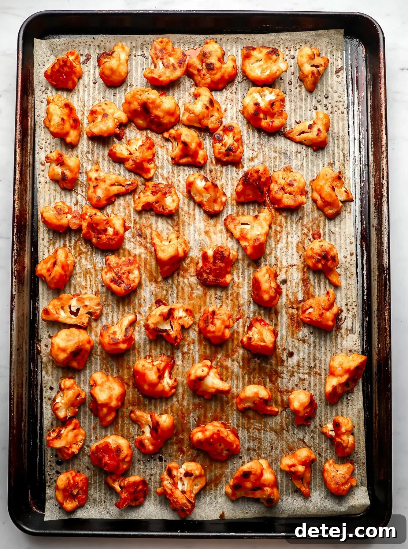 baked buffalo cauliflower wings in rows on a baking sheet.