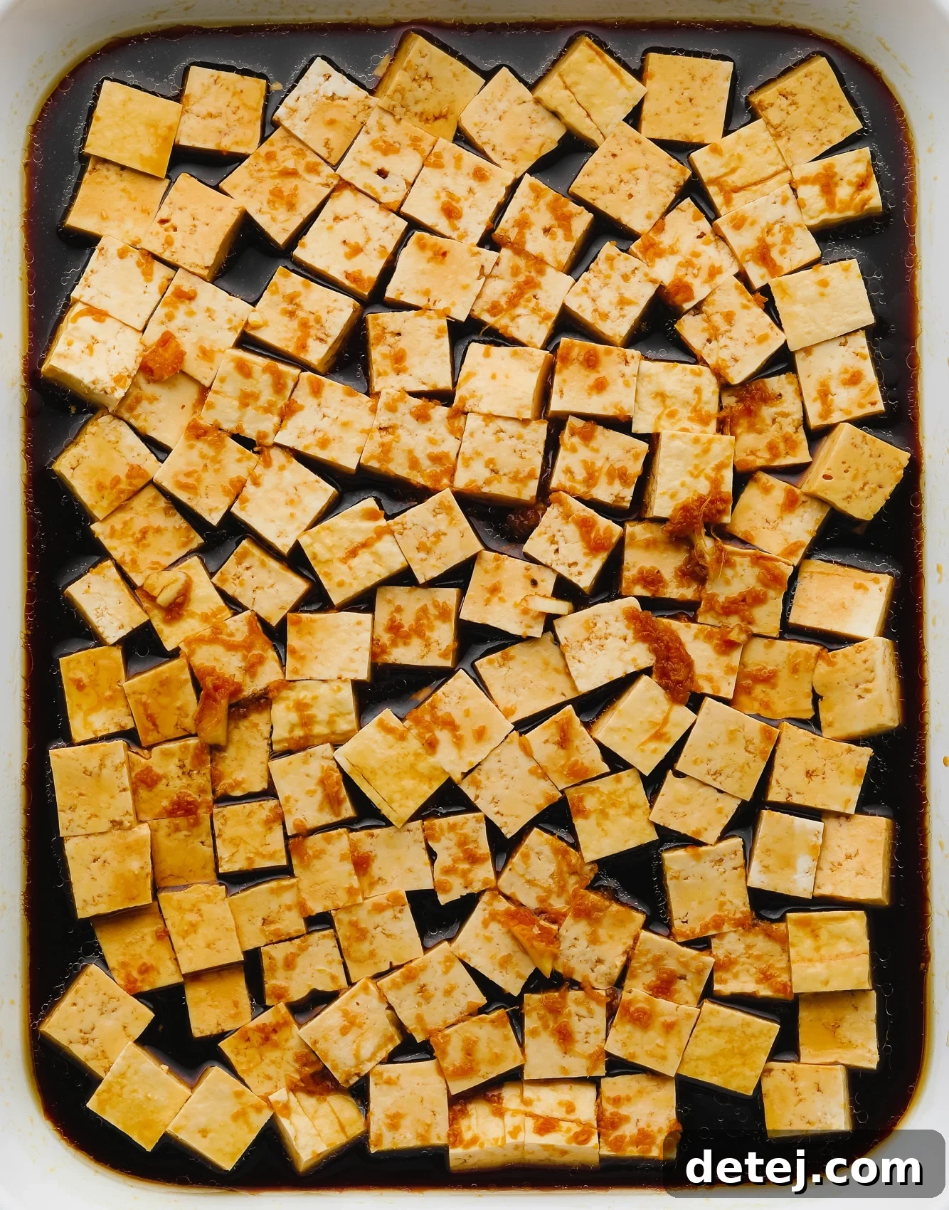 tofu cubes sitting in a dark brown marinade.