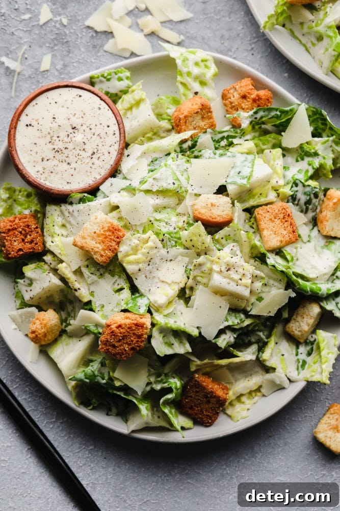 Close-up of a vibrant vegan Caesar salad with crisp romaine, golden croutons, rich dressing, and delicate shaved vegan parmesan.