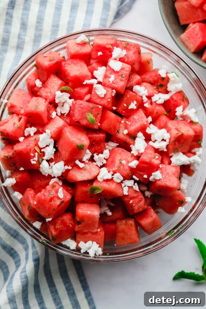 Two vibrant bowls of watermelon salad with feta and fresh mint on a stylish marble backdrop, highlighting its refreshing appeal.