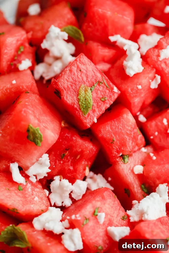 An inviting close-up of a bowl filled with vibrant watermelon cubes, fresh mint leaves, and crumbled feta, ready to be enjoyed.