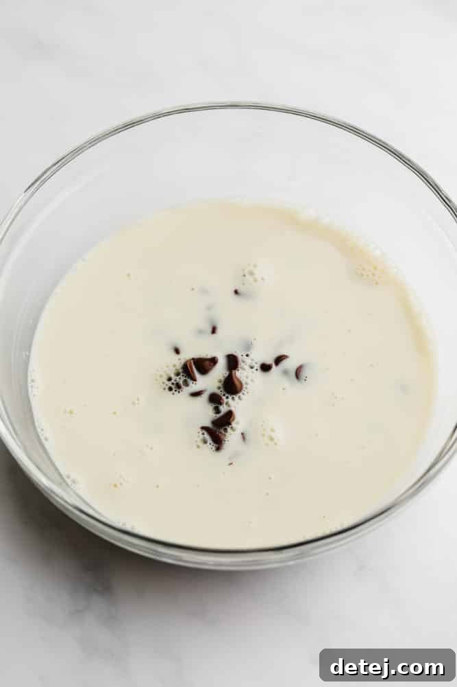 Vegan chocolate chips and soy milk in a glass bowl, ready for ganache preparation