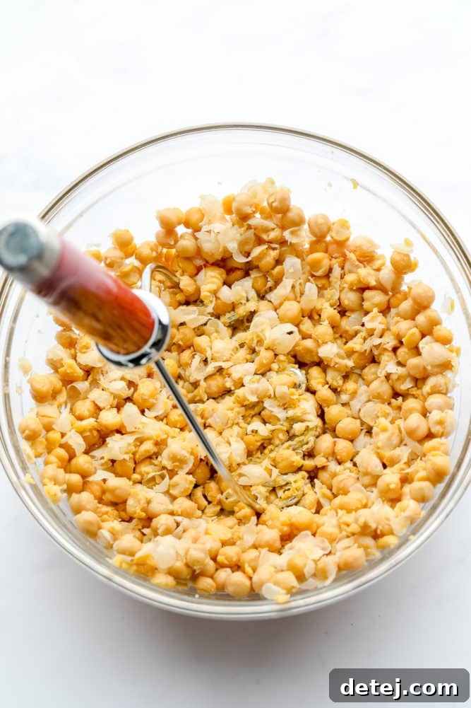 glass bowl with chickpeas being mashed