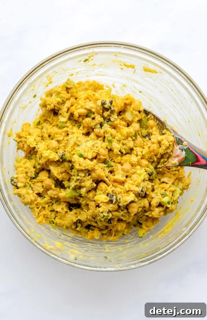 a colorful spoon mixing up chickpeas and other ingredients in a glass bowl