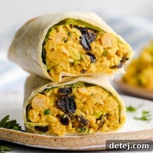 square image of a wrap with bean yellow mixture and raisins on a plate