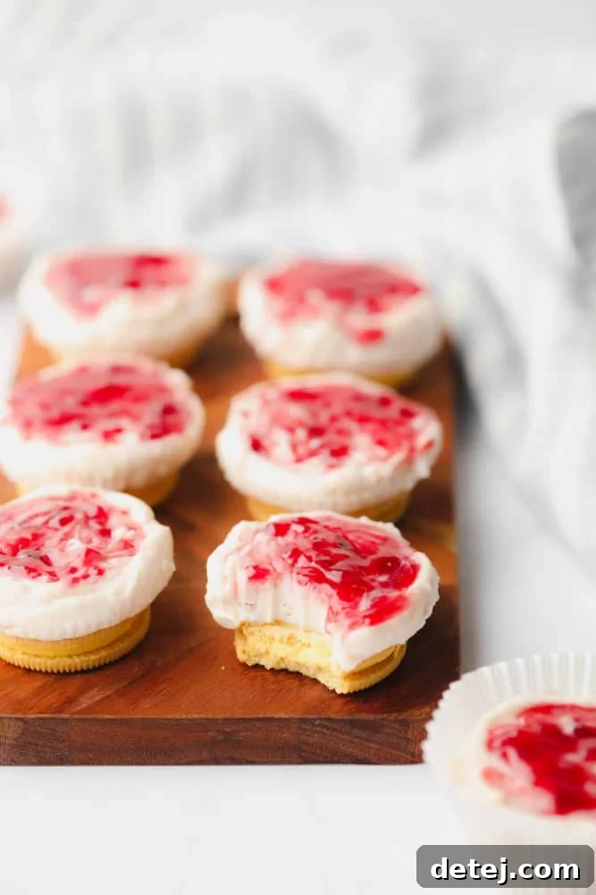 Several perfectly portioned mini raspberry cheesecakes arranged artfully on a white board with a clean background, highlighting their vibrant color and creamy texture.