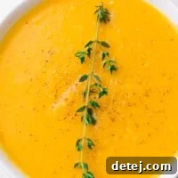 A close-up of a steaming bowl of Instant Pot butternut squash soup, garnished with fresh thyme, inviting warmth and comfort.