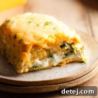 A close-up of a perfectly portioned slice of vegan butternut squash lasagna, showing its vibrant layers and creamy texture on a plate.
