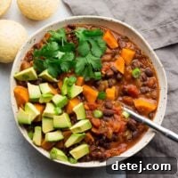A square image of a piping hot bowl of sweet potato black bean chili, ready to be enjoyed on a cool day.