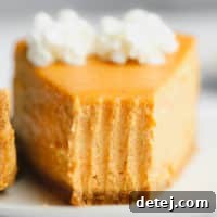 A close-up of a delectable slice of vegan pumpkin cheesecake with a bite missing, showcasing its smooth, creamy layers and a hint of crust.