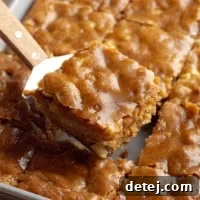 A cake server holding a perfectly cut slice of moist vegan apple cake above the rest of the sliced cake, ready to be served.