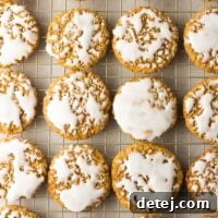 Numerous beautifully iced vegan oatmeal cookies resting on a cooling rack, showing their soft centers and chewy edges.