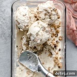 Looking down on several scoops of creamy cookie dough ice cream served in a bowl, set against a grey backdrop with a delicate pink lacy towel accent.